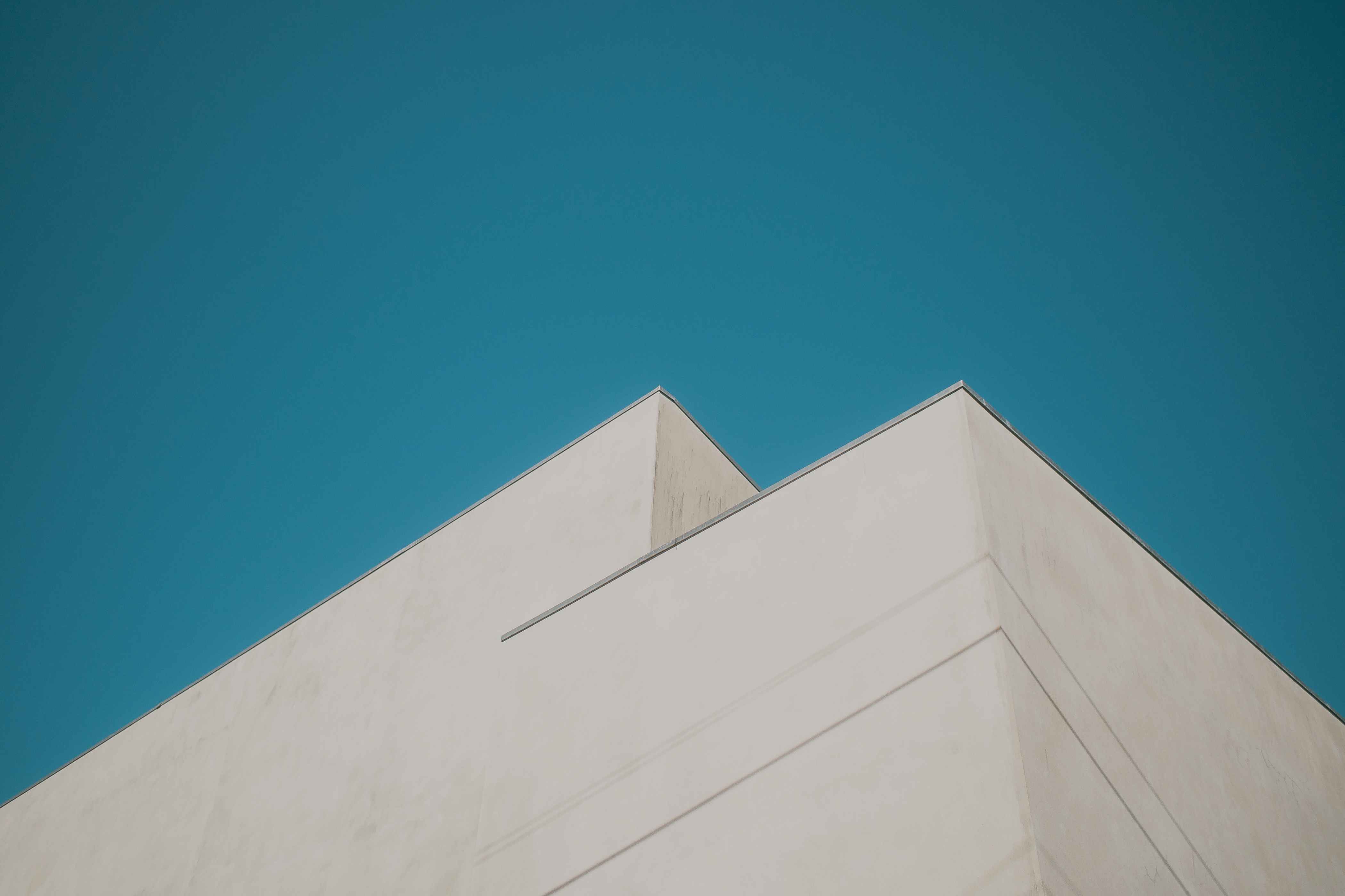 Clean geometric white architectural structures against vibrant teal sky