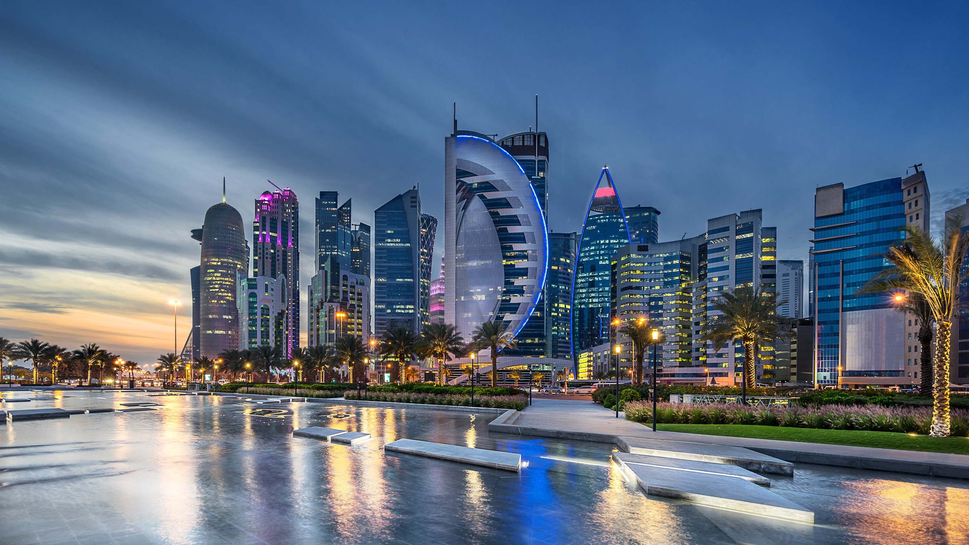 Stunning waterfront view of Doha's West Bay skyline at dusk featuring modern futuristic architecture and illuminated promenade